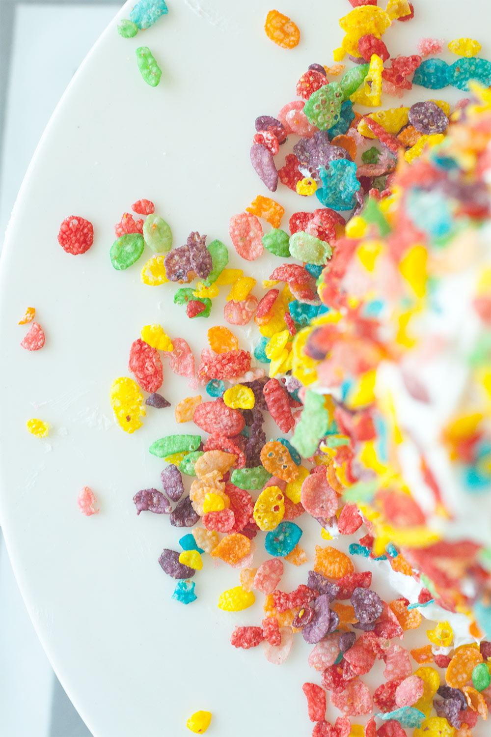 This cake is so party ready it comes with it's own confetti. Strawberry cake, fluffy white frosting, and rainbow breakfast cereal are all you need for this Fruity Pebbles Cake recipe! Pin for later or click through for the recipe.